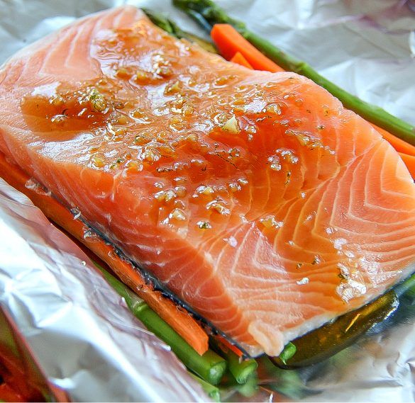 salmon, asparagus and carrots on tinfoil with seasoning in them