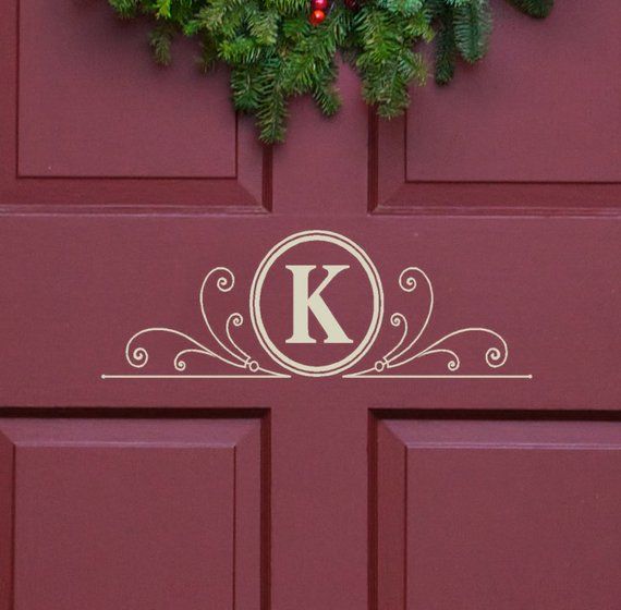 a red door with a wreath on it and the letter k painted in white letters