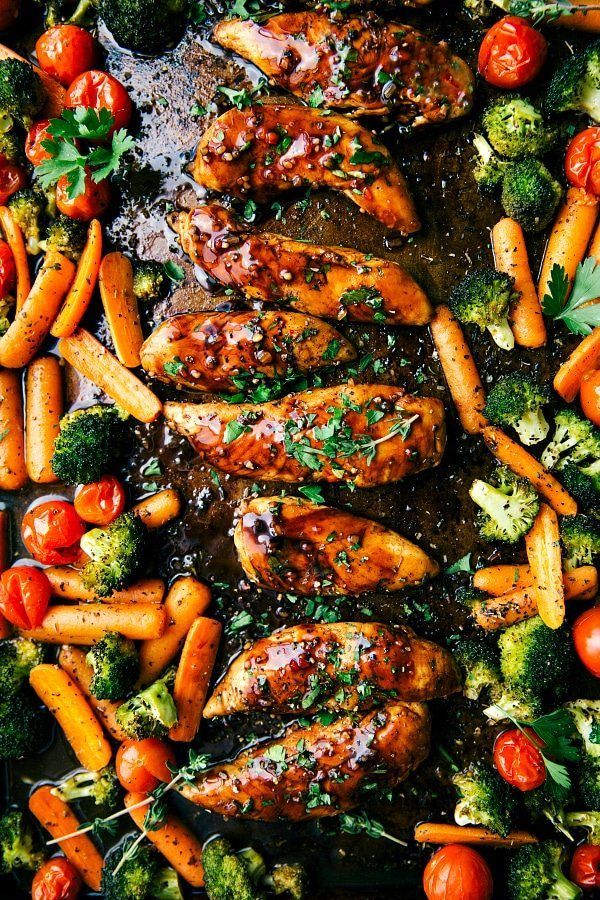 chicken, carrots and broccoli on a baking sheet with sauce in the middle