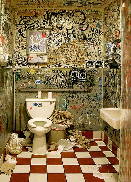 a bathroom that has graffiti all over the walls and floor, with a toilet in it