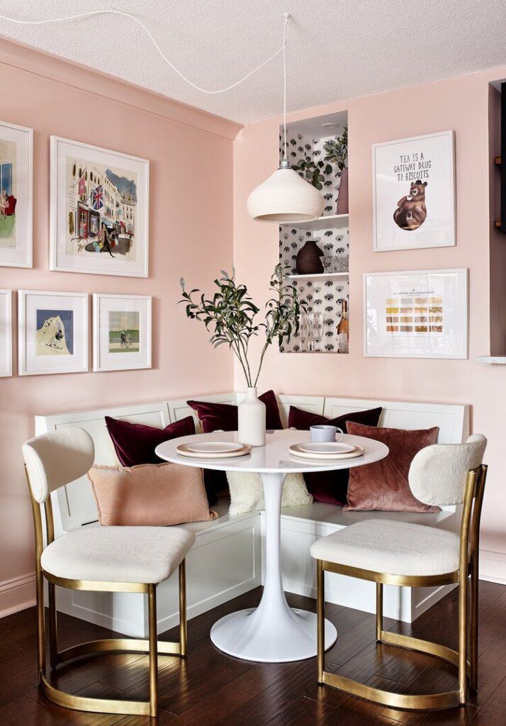 a dining room with pink walls and pictures on the wall