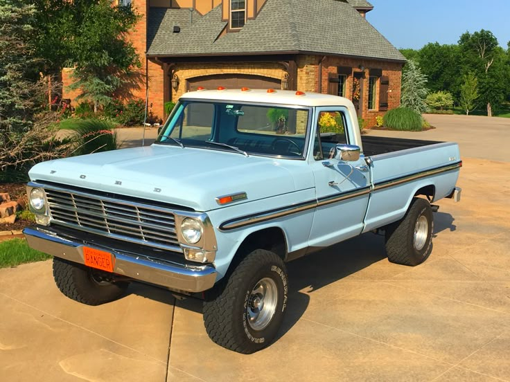 an old blue pickup truck parked in front of a house