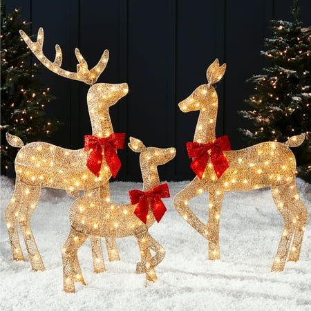 two lighted reindeers in the snow with red bows