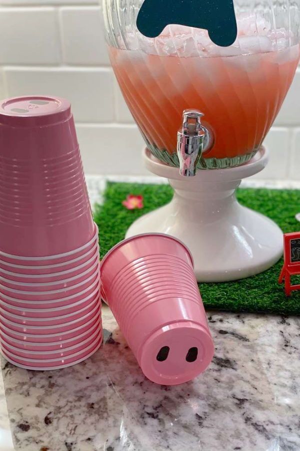 pink cups are stacked on top of each other in front of an ice bucket and a piggy bank