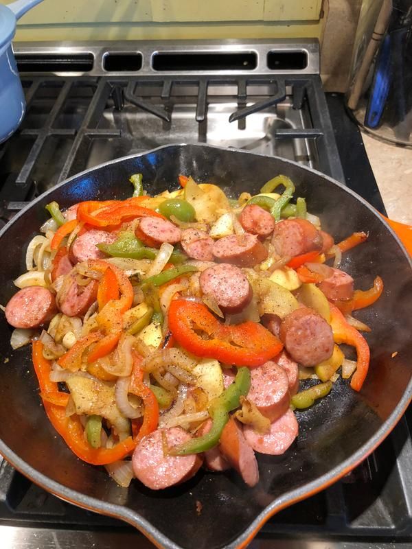 sausage and peppers cooking in a skillet on the stove