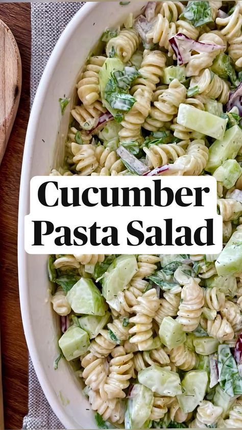 a white bowl filled with pasta salad next to a wooden spoon and knife on top of a table