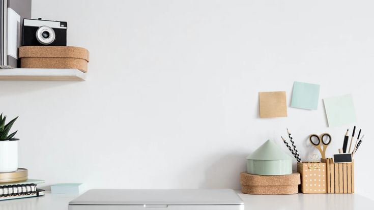 a laptop computer sitting on top of a white desk next to a potted plant