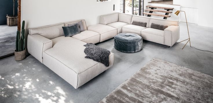 a living room with a large sectional couch and rugs on the floor in front of it