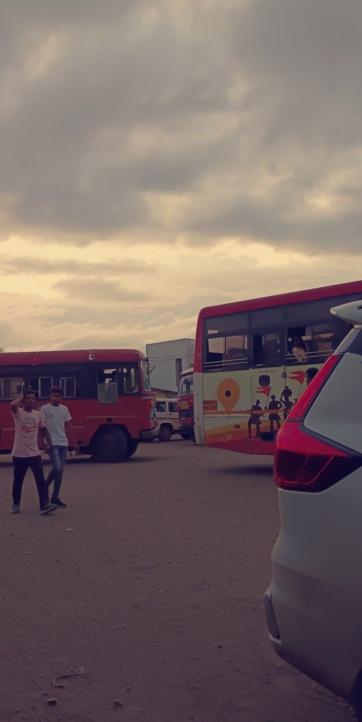 several buses parked in a parking lot with people walking by them and one person standing next to the car