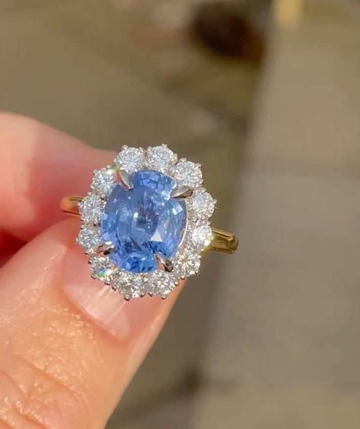 a close up of a person's hand holding a ring with a blue and white stone