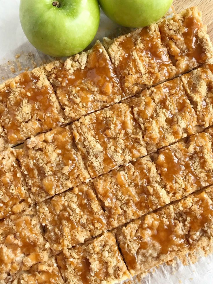 two green apples sitting on top of a cutting board next to squares of oatmeal