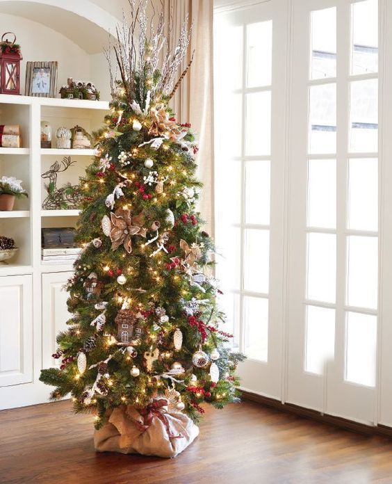 a decorated christmas tree in the corner of a room with white walls and wooden floors