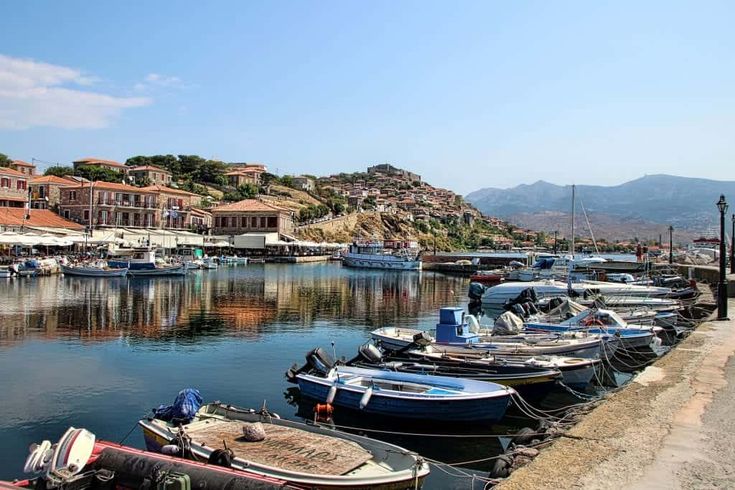 several boats are docked in the water near some buildings and hills on either side of the river