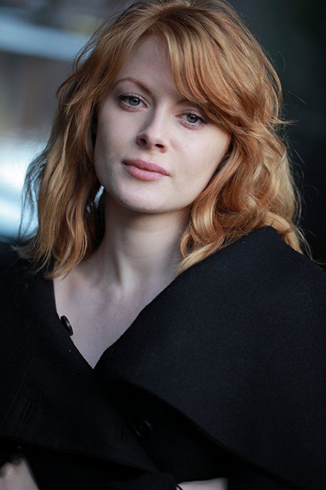 a woman with red hair wearing a black coat