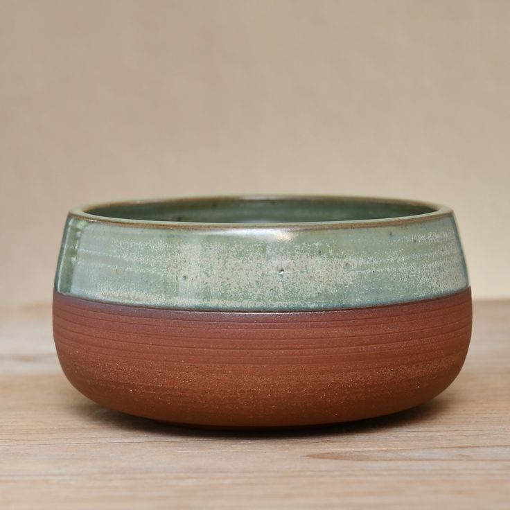 a brown and green bowl sitting on top of a wooden table