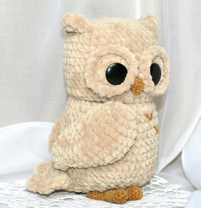 an owl stuffed animal sitting on top of a white doily with eyes wide open