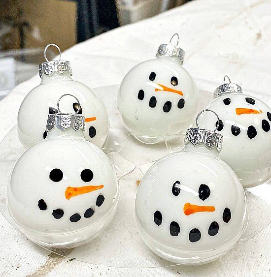 four glass snowman ornaments sitting on top of a table