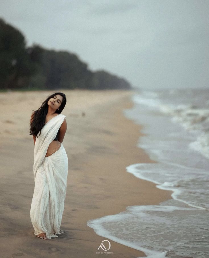 a woman in a white dress standing on the beach