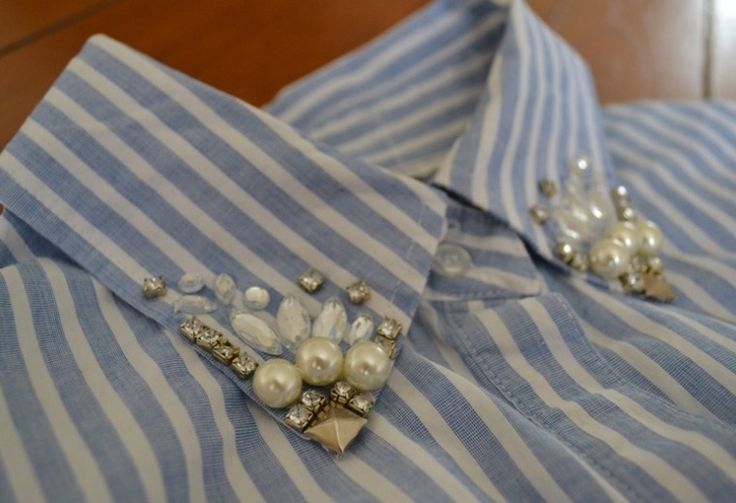 a blue and white striped shirt with some pearls on the lapel, along with other pins