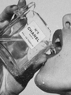 black and white photograph of a person holding a bottle of chanel no 5 perfume