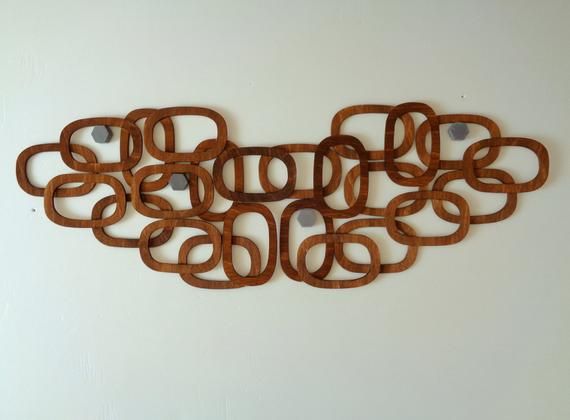 a wall sculpture made out of wooden circles on a white wall with two holes in the middle