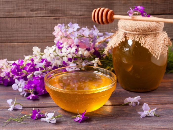 a jar of honey next to some flowers