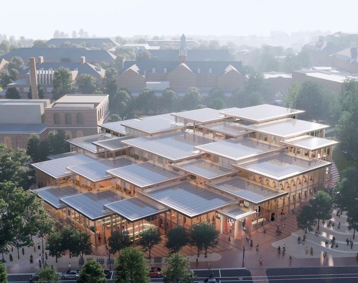 an aerial view of a building with lots of glass on the front and sides, surrounded by trees