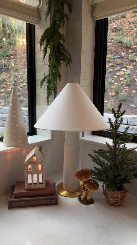 a lamp that is sitting on a table next to a potted plant and tree