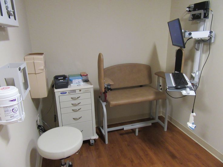 a medical room with a chair, laptop and other equipment on the wall next to it