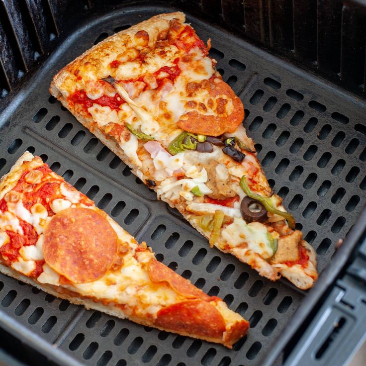 two slices of pizza sitting on top of a black grill grate next to each other