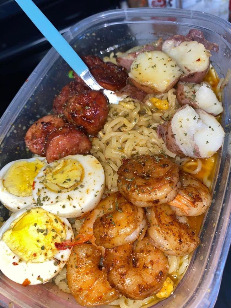 a plastic container filled with pasta, shrimp and eggs on top of it's side