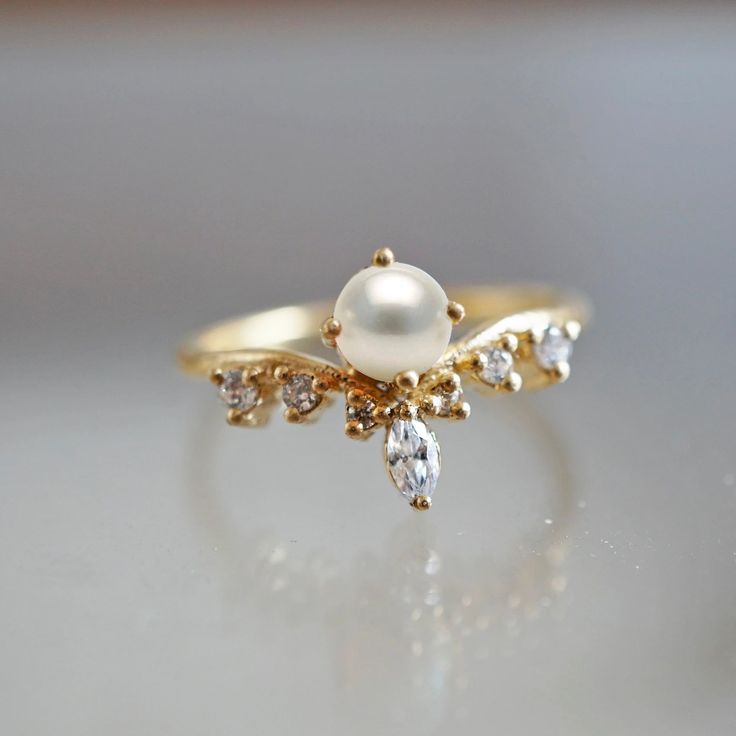 a pearl and diamond ring on a table