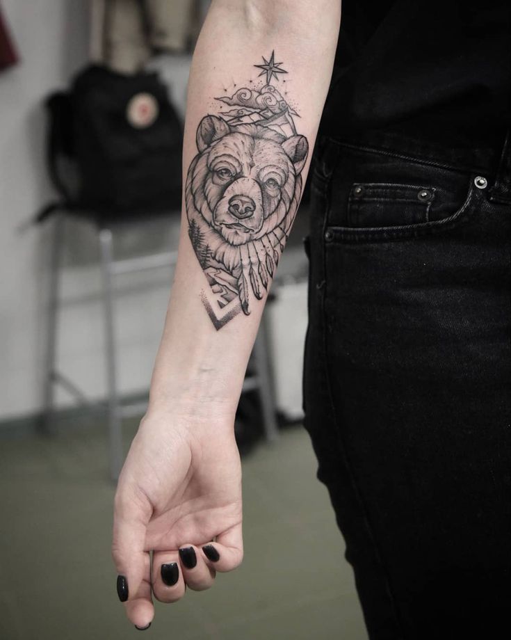 a woman's arm with a bear and star tattoo on the left side of her arm