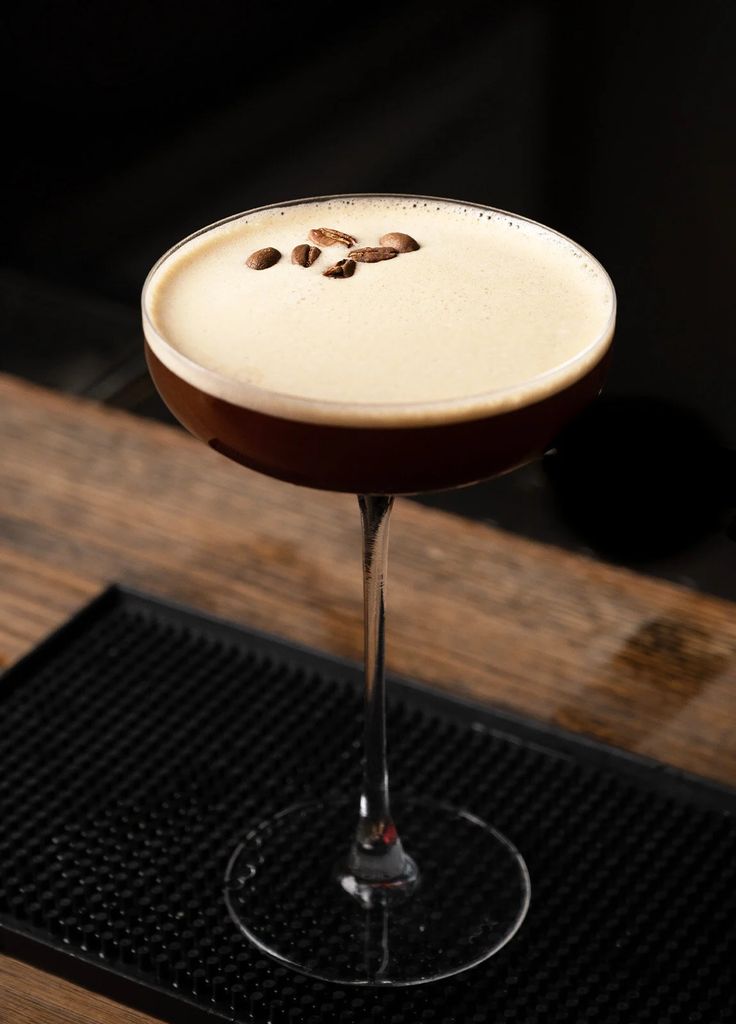 a chocolate martini with nuts on the rim and garnished in white liquid, sitting on a wooden table