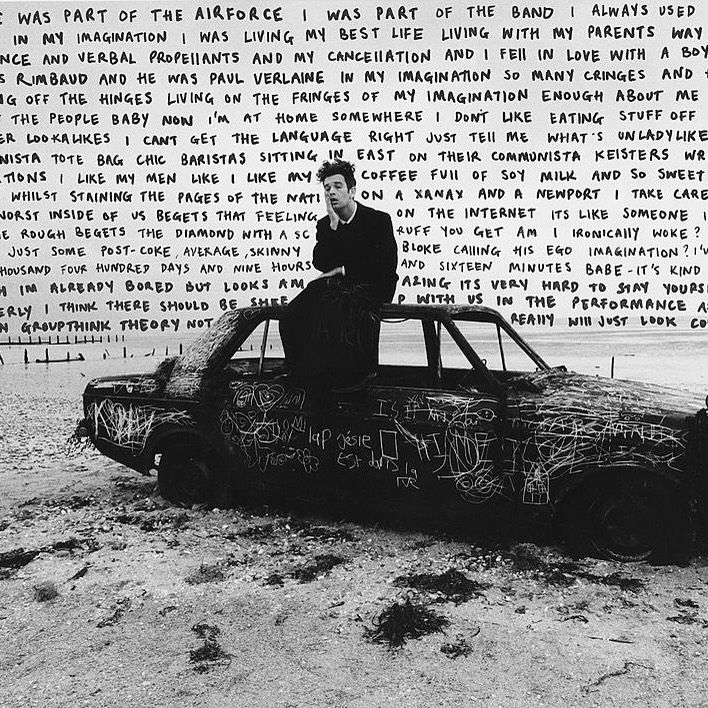 a man sitting on top of a car in the desert with words written all over it