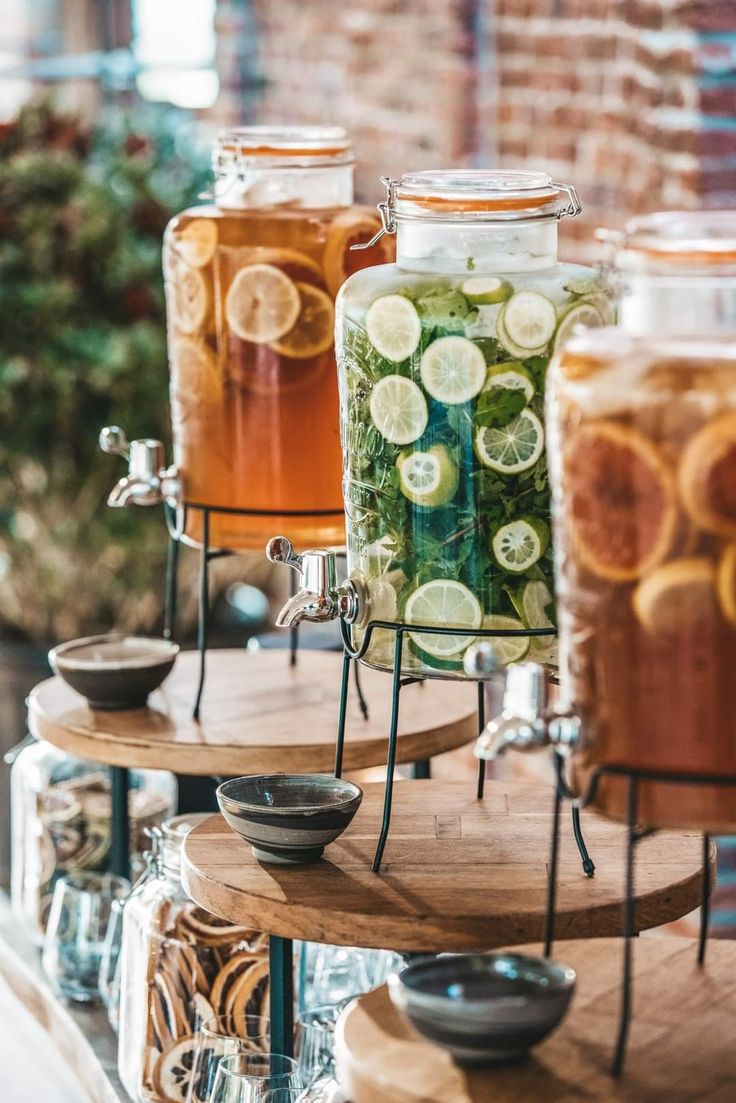 three jars filled with different types of drinks on top of wooden trays next to each other