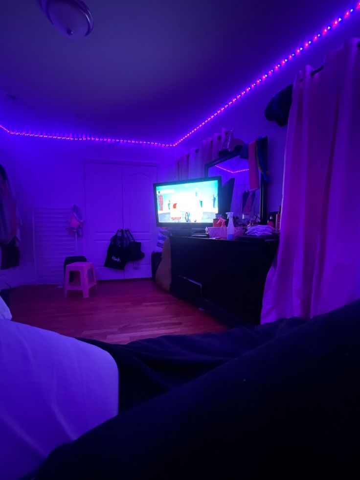 a bedroom with purple lights and a television