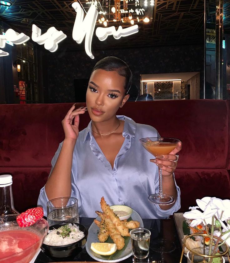 a woman sitting at a table with food and drinks