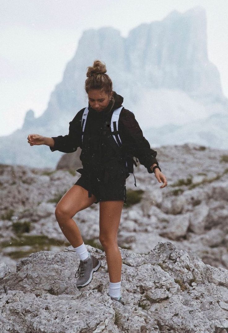 a woman standing on top of a rocky mountain