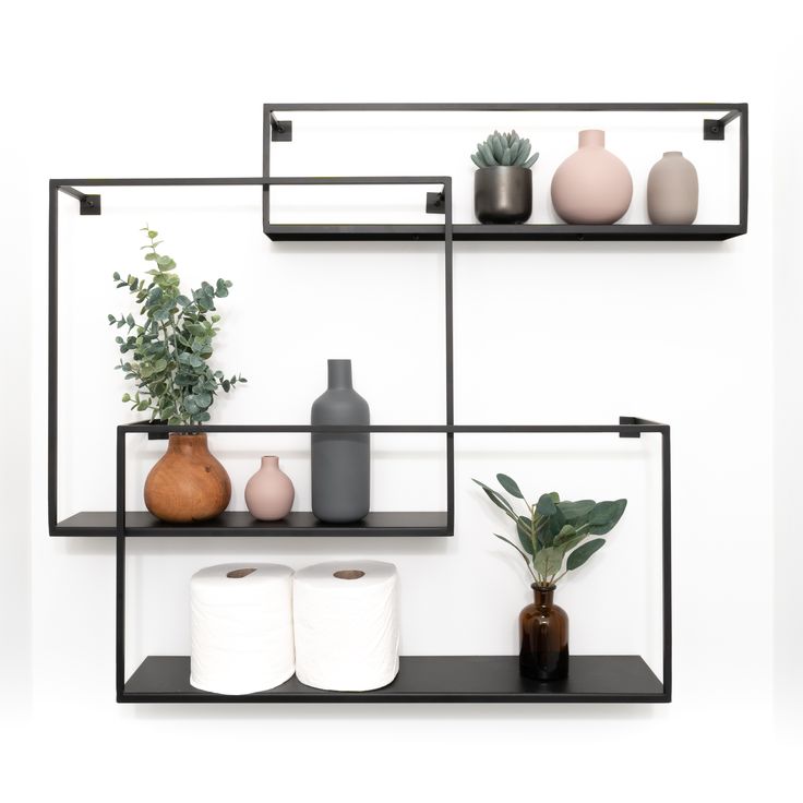 three shelves with toilet paper and vases on them