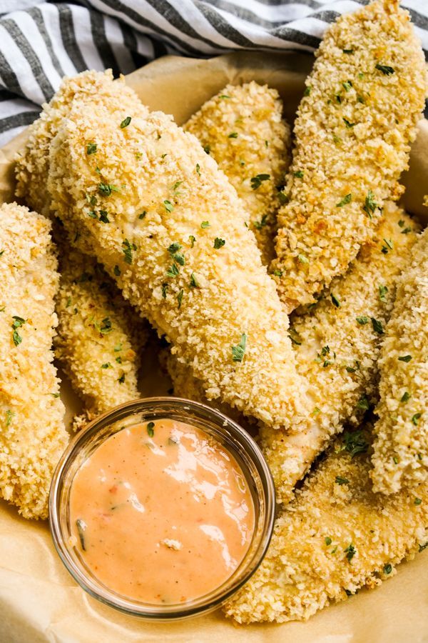 baked parmesan chicken tenders on a plate with dipping sauce in the middle