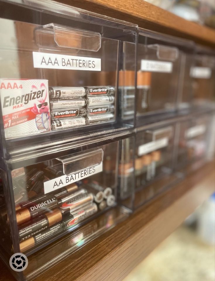 some batteries are sitting in plastic bins on the shelf with labels that read aa batteries