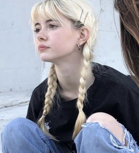 a woman with long blonde hair sitting on the ground