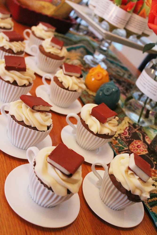 small cupcakes with white frosting and chocolate toppings sit on saucers