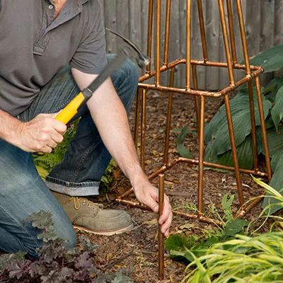 a man kneeling down in front of a birdcage holding a yellow handled tool