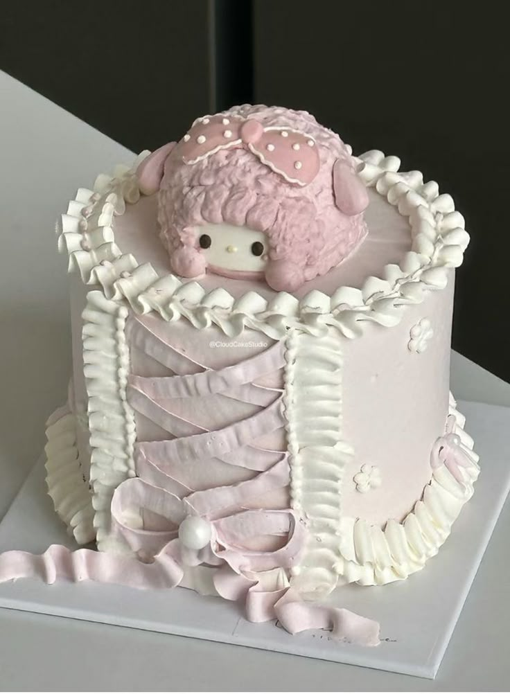 a pink and white cake with a teddy bear in the center on top of it