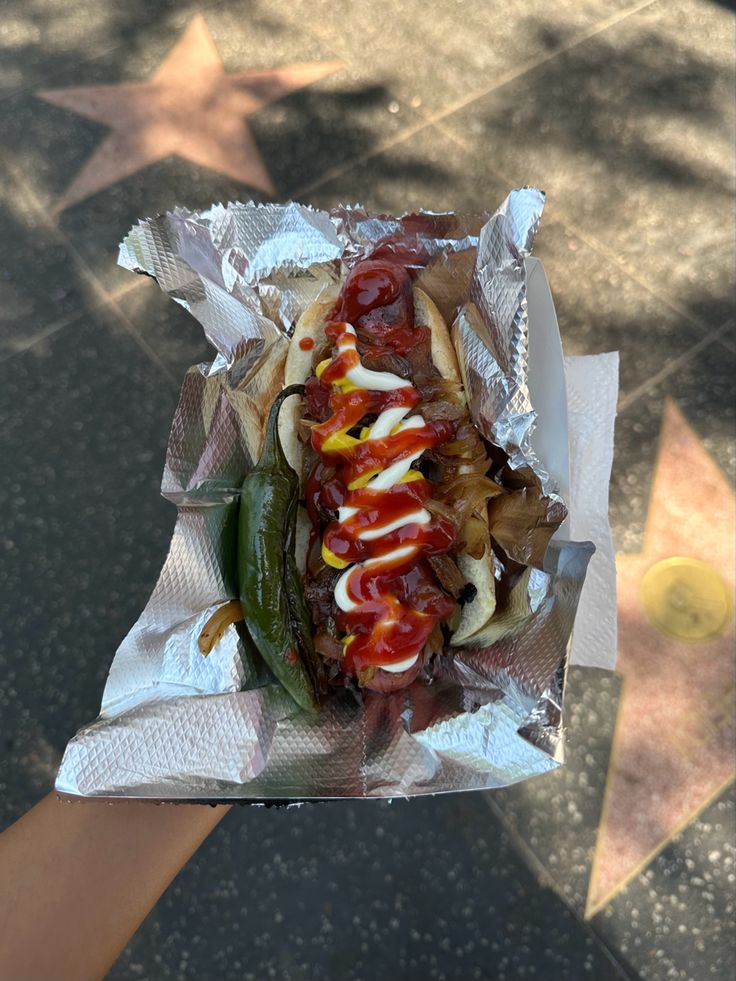 a hot dog covered in ketchup, mustard and relish sitting on top of aluminum foil