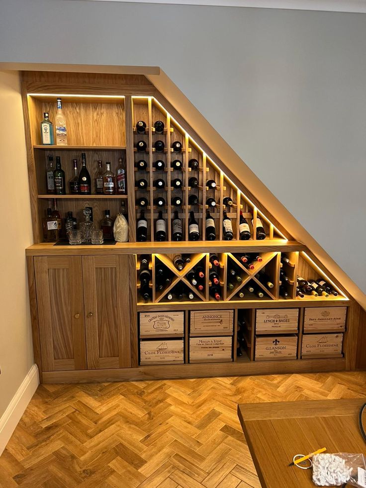 a wine cellar in the corner of a room under a slanted wall with shelves and drawers