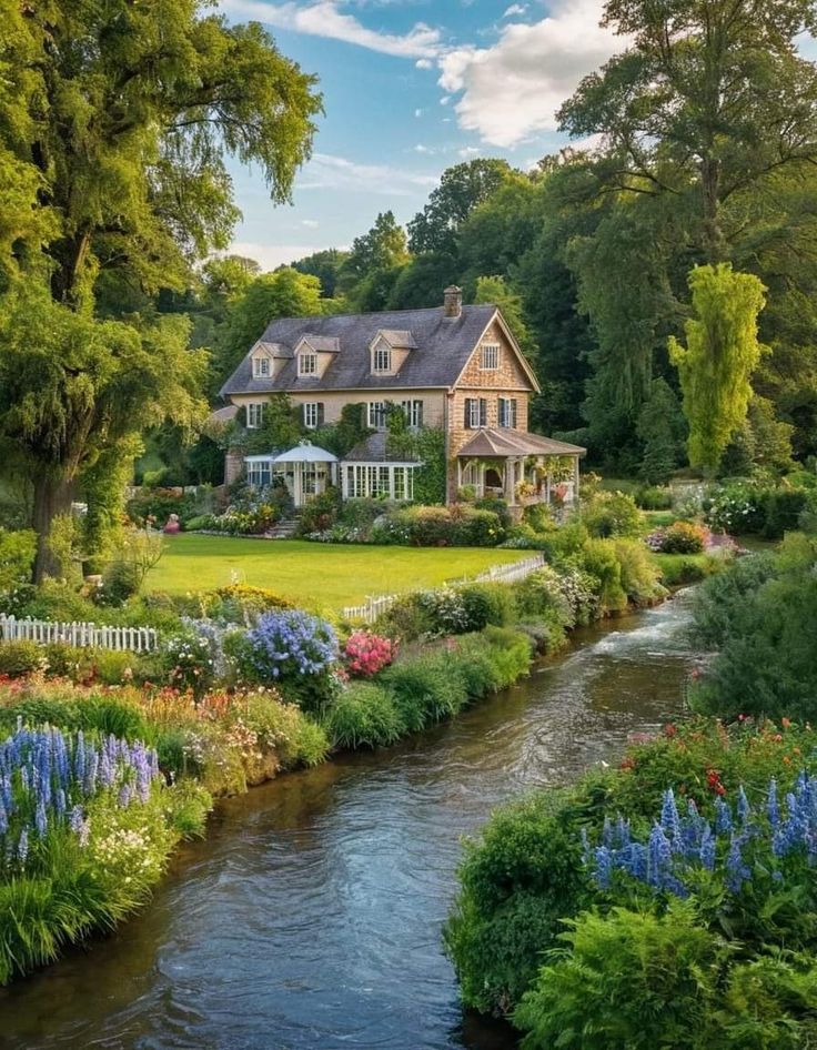 a large house sitting in the middle of a lush green field next to a river