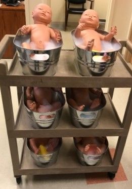 three baby dolls are sitting in buckets on a cart